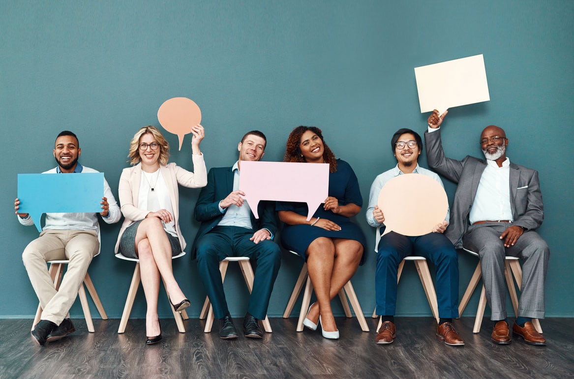 Shot portrait of a diverse group of businesspeople holding up speech bubbles while they wait in line
